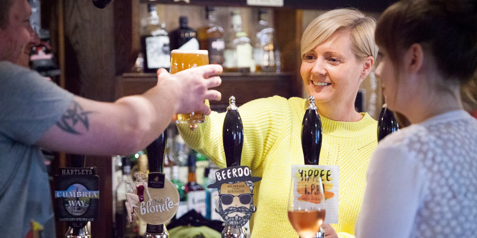 Lady smiling whilst serving beer