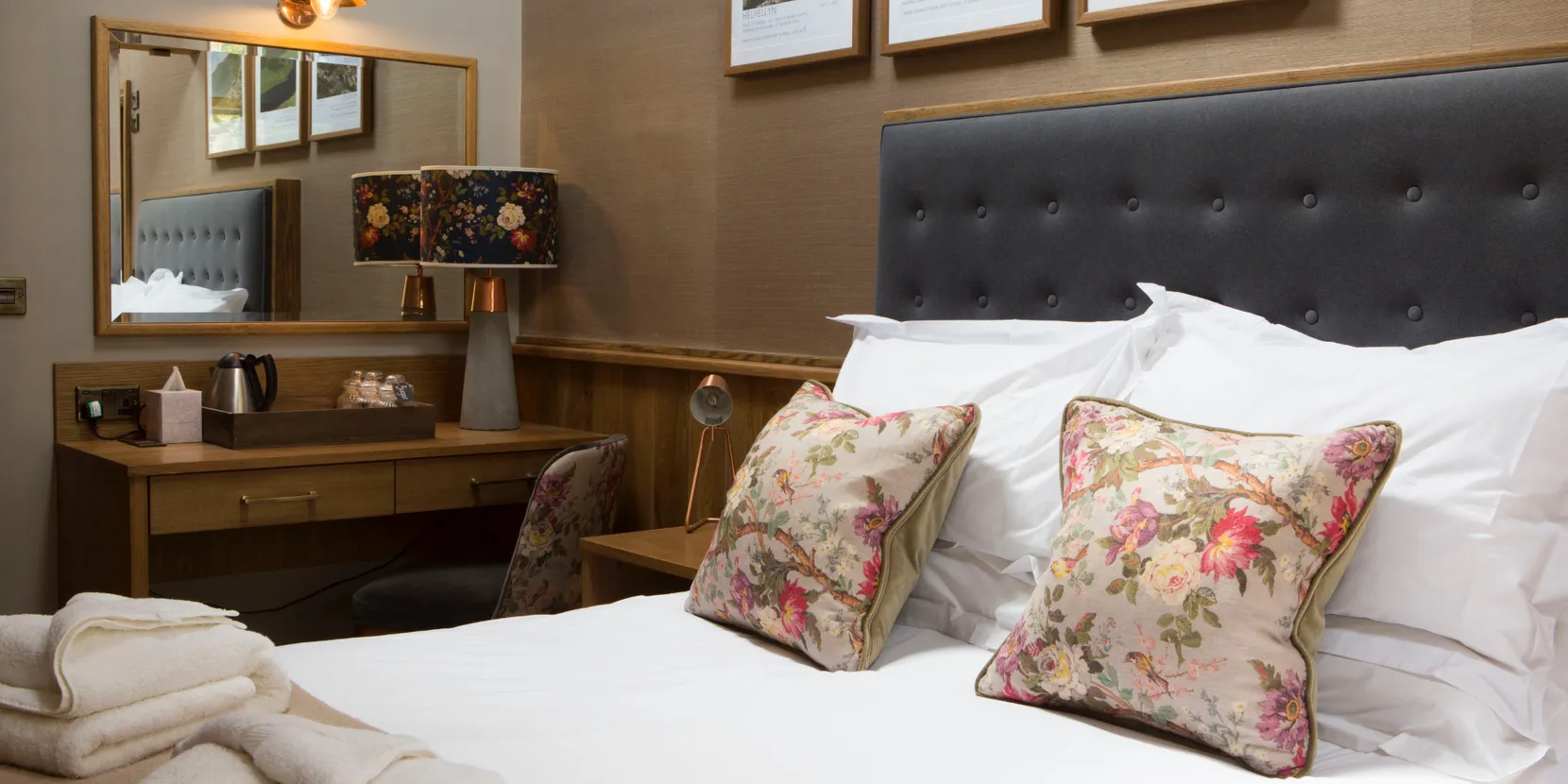A bed which is mainly white. The pillows are patterned.