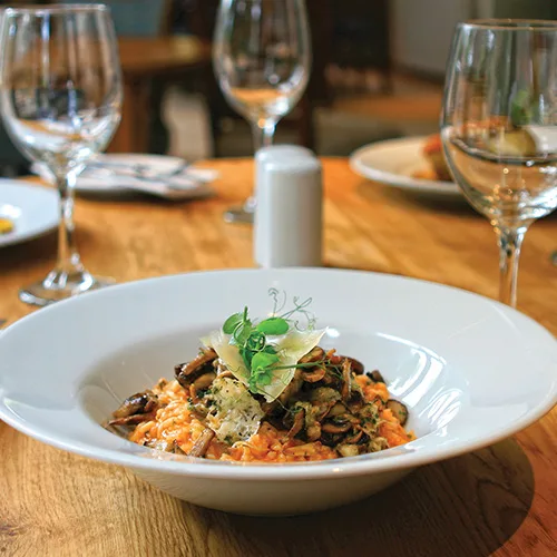 Mushroom risotto in a white bowl on a set dining table
