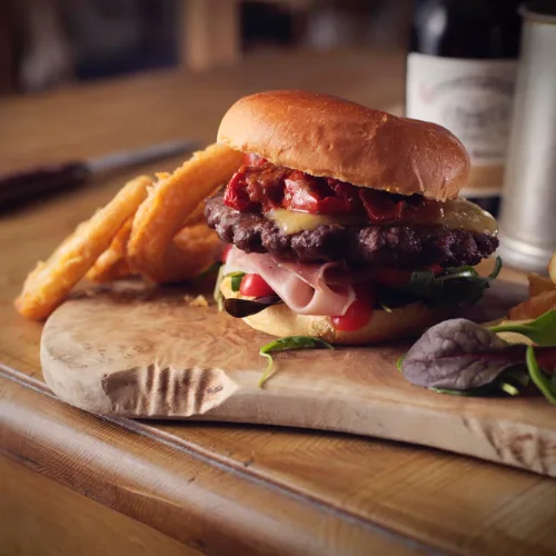 Gourmet burger with onion rings on a wooden board
