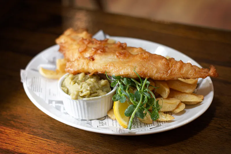 Battered fish and chips with mushy peas and lemon