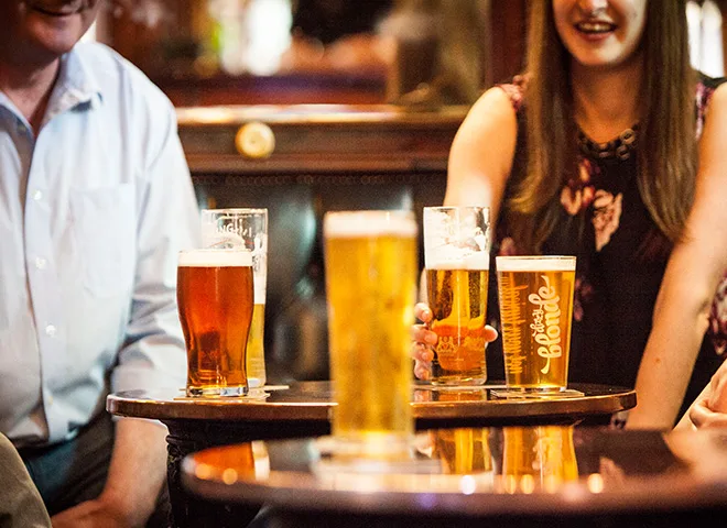 Two people sitting behind four beers