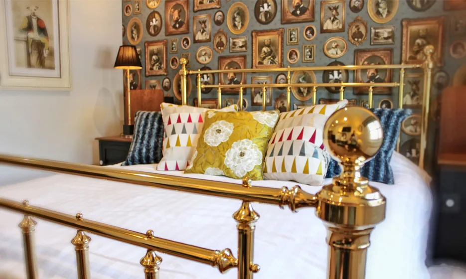 A bed which is mainly white. The pillows are patterned.