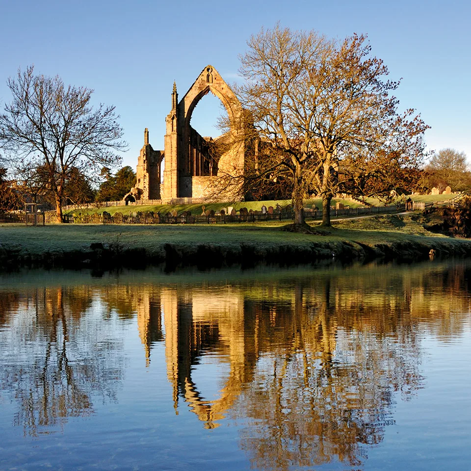 Bolton Abbey ruins reflected in the River Wharfe at golden hour